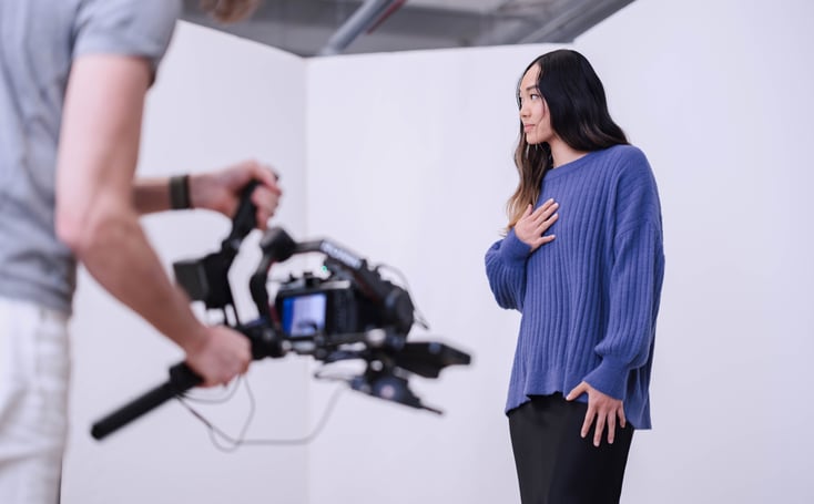 Image of a female model on set in a blue sweater