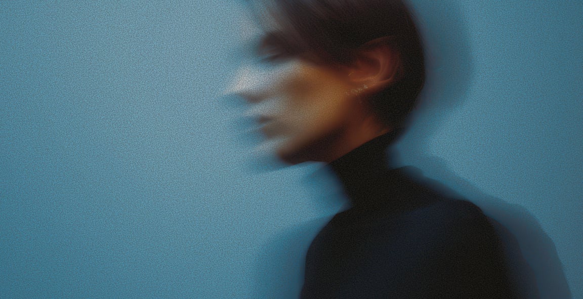 A motion-blurred portrait against a blue wall