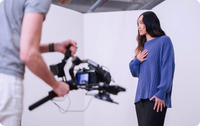 A camera operator filming a model on a studio set